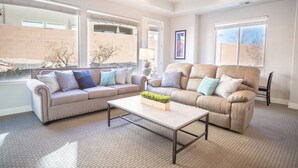 A living room with two sofas, a coffee table, and large windows. - Spacious backyard & 2 pools/spas, fishing pond (Washington)