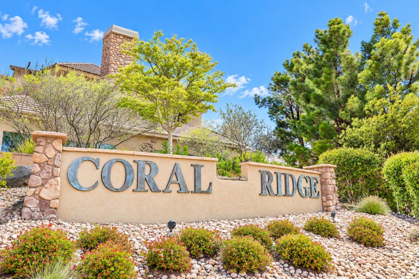 Un letrero que dice 'CORAL RIDGE', con un muro de piedra y jardines.