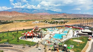 An aerial view of a water park with multiple pools, slides, and a large water slide structure. - Spacious backyard & 2 pools/spas, fishing pond (Washington)