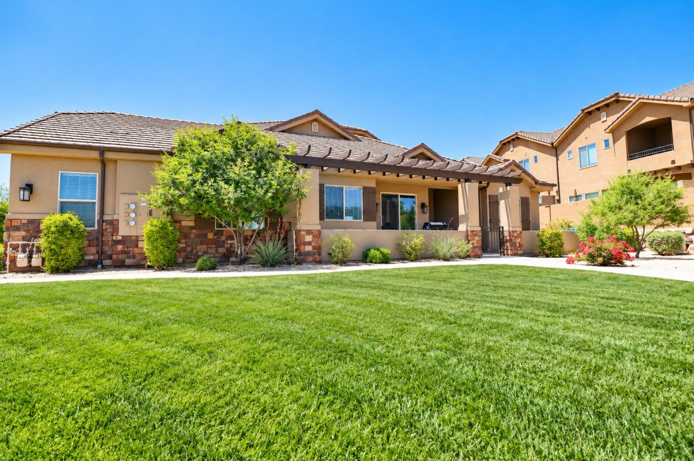 A residential building with a well-maintained lawn, a patio area, and a variety of landscaping.