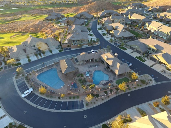 A residential area with a central swimming pool, multiple houses, and a curved road.