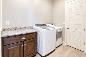 A laundry room with a washing machine and dryer, wooden cabinets, and a white door. - Spacious backyard & 2 pools/spas, fishing pond (Washington)