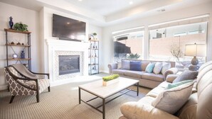 A living room with a fireplace, a sofa, a coffee table, and a chair. - Spacious backyard & 2 pools/spas, fishing pond (Washington)