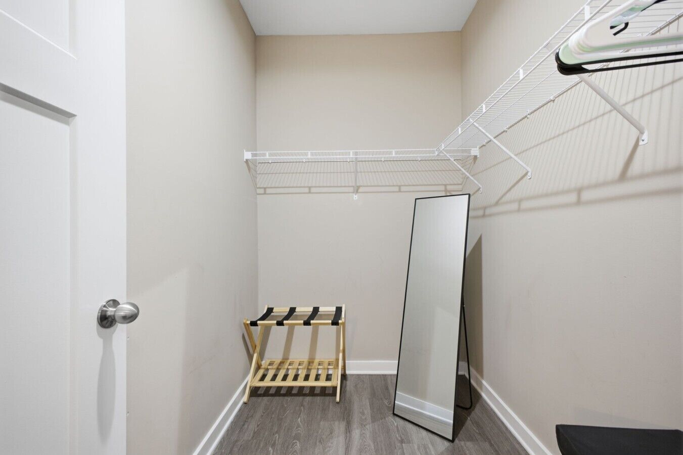 Een kleine kamer met een garderobe, een spiegel en een droogrek.
