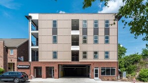 Un immeuble à plusieurs étages avec une entrée de garage, une façade en briques et une enseigne sur laquelle on peut lire « The Charlesville ».