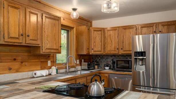 Une cuisine avec des meubles en bois, un réfrigérateur en acier inoxydable, une cuisinière et un four à micro-ondes.