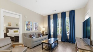 A living room with a sofa, armchairs, a coffee table, a TV, and a bed in the adjacent room. - 1 mile walk to Broadway! 2 Bd*2 Bth  #303 (Nashville)