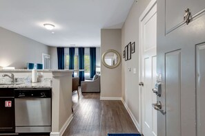 A modern kitchen with a dishwasher, a dining area with a round mirror, and a hallway leading to a door. - *1 mi Walk to Downtown*2 Bd 2Bth Sleeps 6* #301 (Nashville)