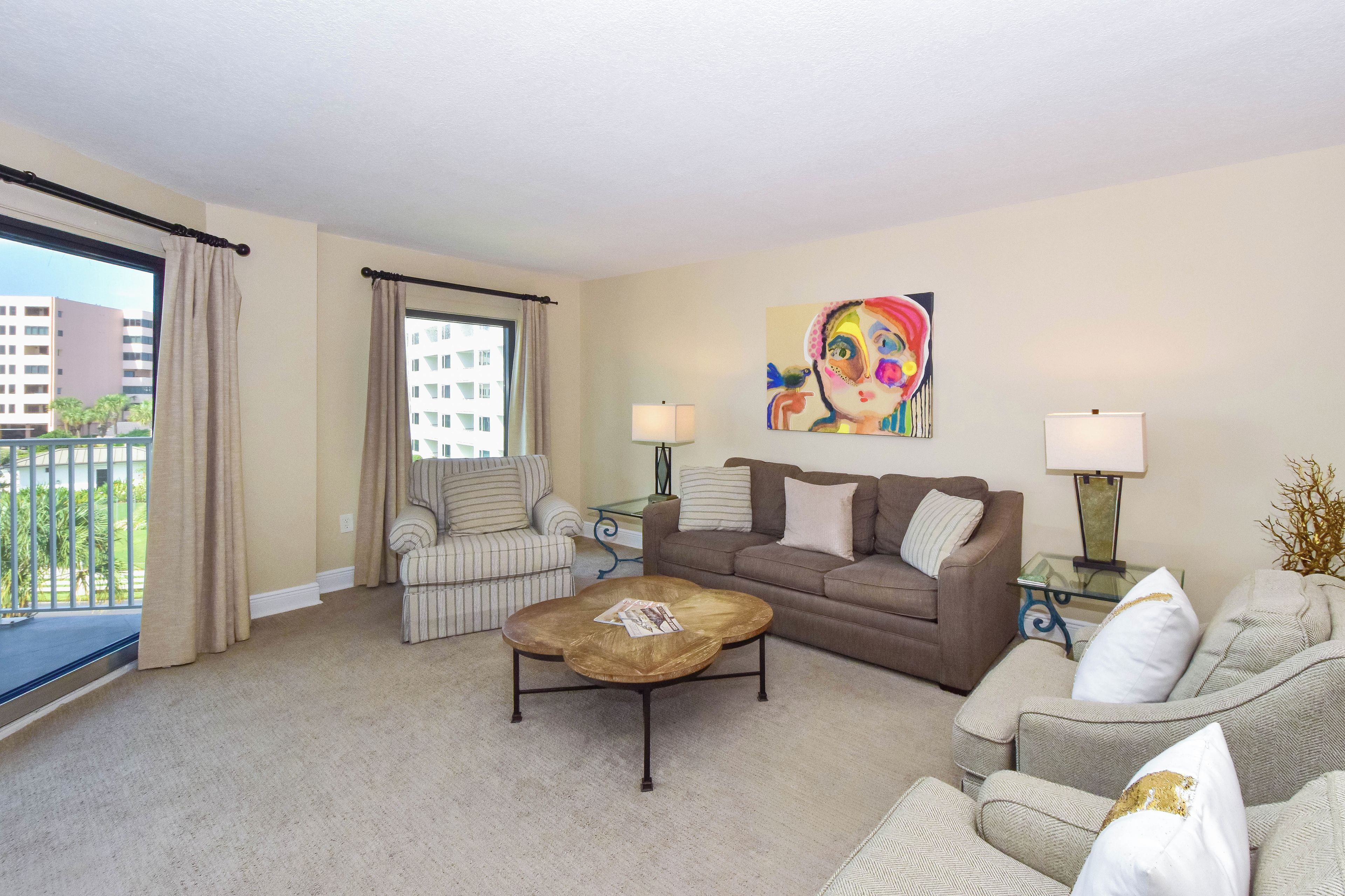 A living room with a striped armchair, a brown sofa, a coffee table, and a painting on the wall.