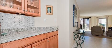 A kitchen with wooden cabinets, a marble countertop, and a dining area with a table and chairs.