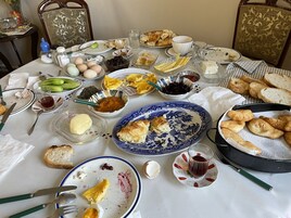 Una mesa dispuesta con varios platos, incluyendo pan, huevos y un tazón de mermelada.