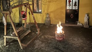 A courtyard with a swing set, a statue, and a lit fire pit. - Mavi Ladin Konukevi (Kars)