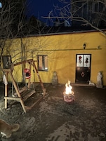 Un patio con un columpio, una estatua y una fogata encendida.