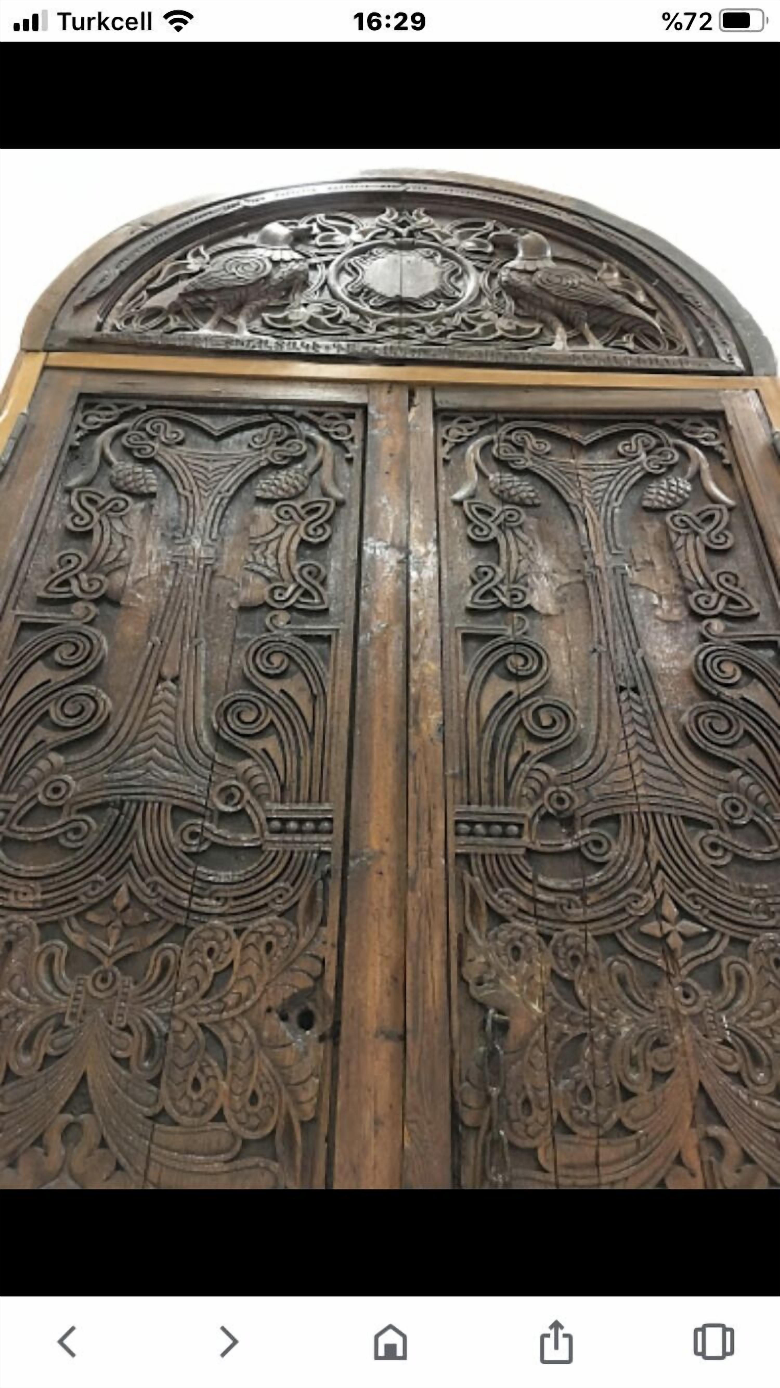 Una puerta de madera con tallas intrincadas y un escudo decorativo encima.