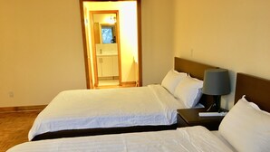 Et hotelværelse med to senge, et natbord med en lampe, og et badeværelse, der kan ses gennem en åben dør.