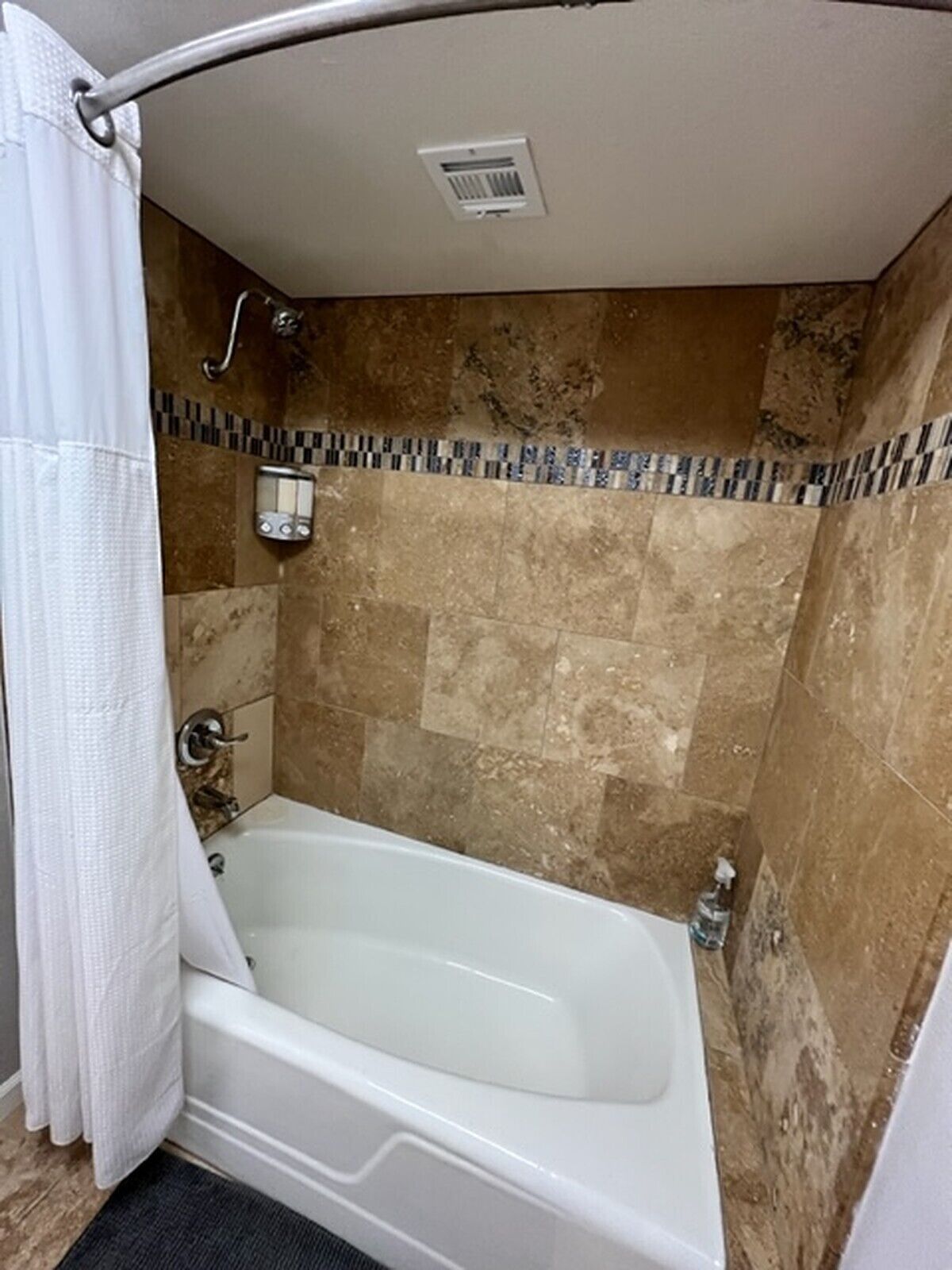 A bathroom with a bathtub, shower, and tiled walls.
