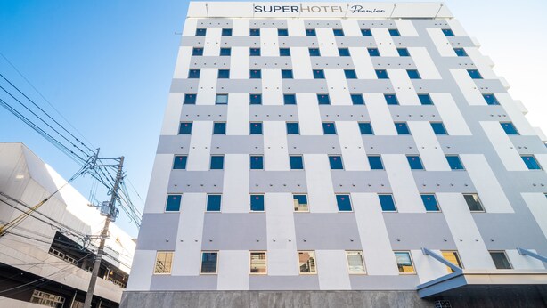 Un edifici d'hotel alt amb un disseny modern, que destaca un cartell al capdamunt que diu "SUPERHOTEL Premier".