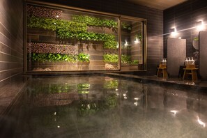A modern bathroom with a glass wall displaying lush greenery, a reflective floor, and a minimalist design. - Super Hotel Premier Miyazaki Ichibangai (Miyazaki)