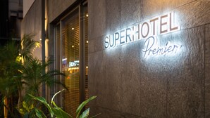 A hotel sign with the name "SuperHotel Premier" illuminated against a stone facade. - Super Hotel Premier Miyazaki Ichibangai (Miyazaki)
