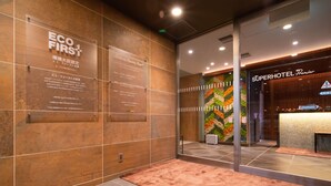A hotel lobby with a reception desk, a wall with a vertical garden, and informational plaques on the wall. - Super Hotel Premier Miyazaki Ichibangai (Miyazaki)