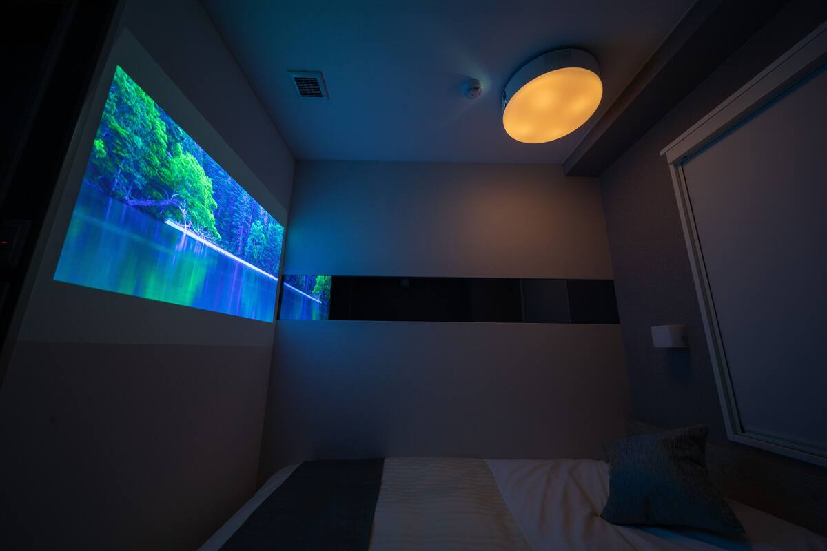 Ein modernes Schlafzimmer mit einem Bett, einem Wandfernseher und einer Deckenleuchte.