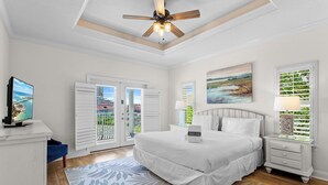 Una camera da letto con un letto, comodini, una ventola a soffitto, un quadro e vista dalla finestra.