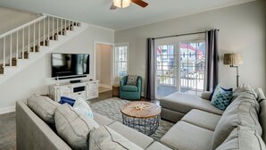 A living room with a staircase, a television, a sofa, a coffee table, and a ceiling fan.