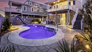 A two-story house with a backyard pool, a slide, and a hot tub.