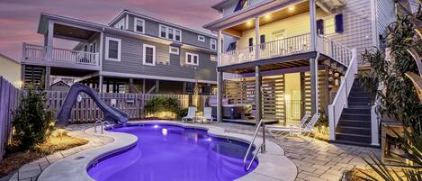 A two-story house with a backyard pool, a slide, and a hot tub.