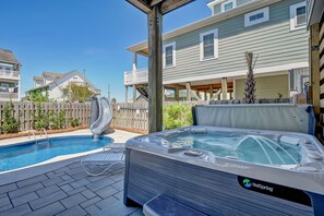 Um quintal com piscina, ofurô e deck de madeira.