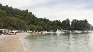 A beach with a sandy shore, umbrellas, and a lifeguard tower. - Holiday home with panoramic view and large terrace (Lovran)