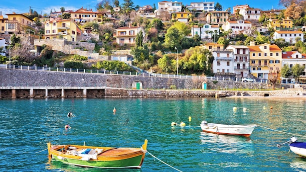 A coastal town with buildings on a hillside, a stone wall, and boats in the water. - Holiday home with panoramic view and large terrace (Lovran)