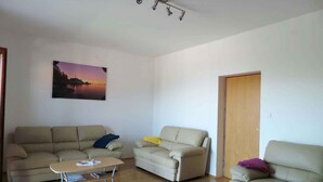 A living room with two sofas, a coffee table, and a painting on the wall. - Holiday home with panoramic view and large terrace (Lovran)