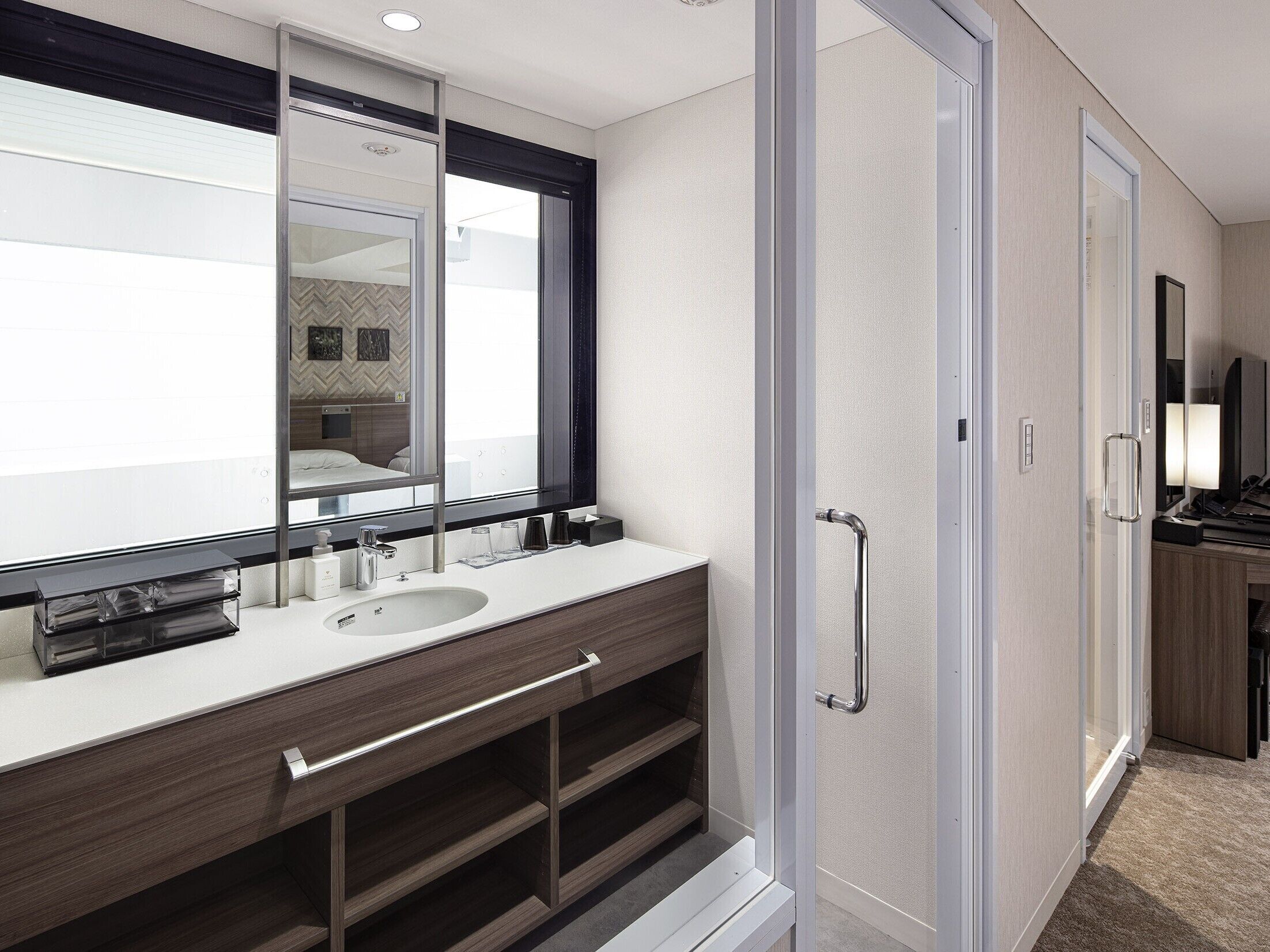 Un bagno moderno con un ampio specchio, due lavabi e una doccia a filo pavimento.