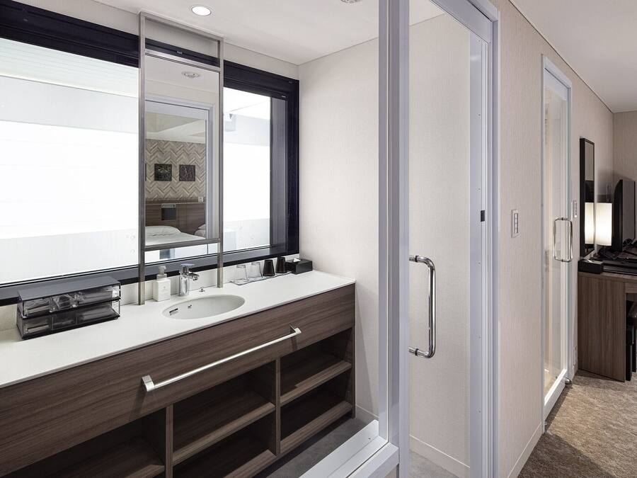 A modern bathroom with a large mirror, two sinks, and a walk-in shower.