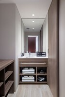 Een moderne badkamer met een houten wastafelmeubel, een grote spiegel en planken met handdoeken.