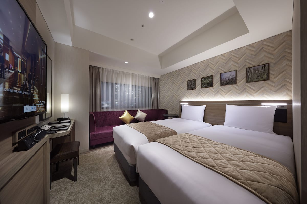 Une chambre d’hôtel avec un grand lit, un bureau avec un ordinateur, une télévision et un canapé.