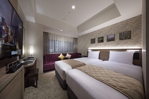 Habitación de hotel con una cama grande, un escritorio con una computadora, un televisor y un sofá.