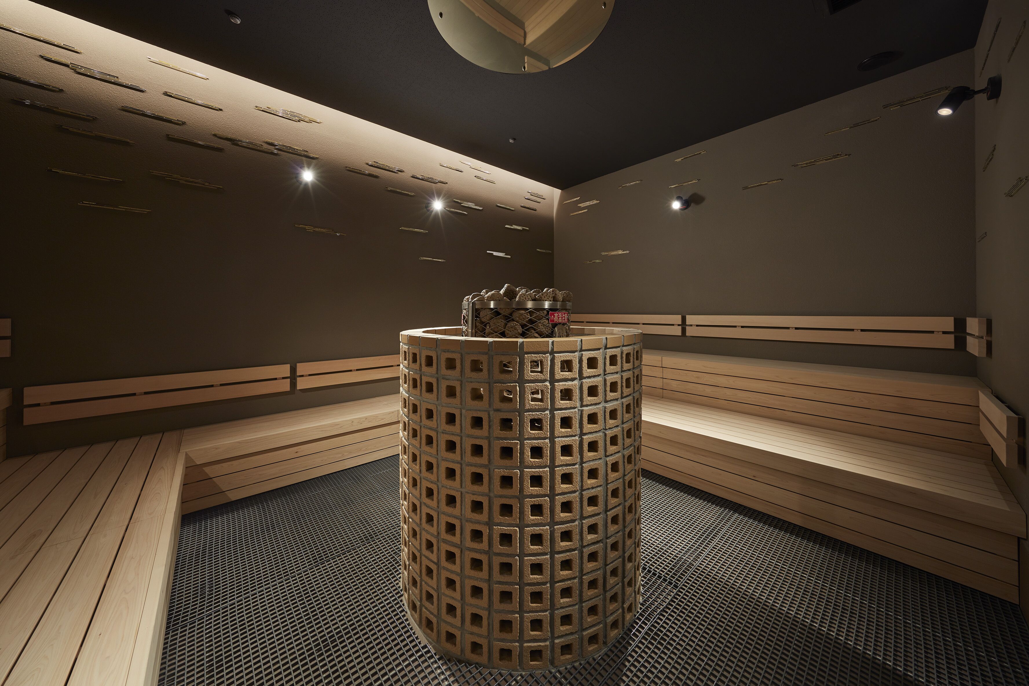 Un sauna doté d’un pilier central, de bancs et d’un luminaire au plafond.