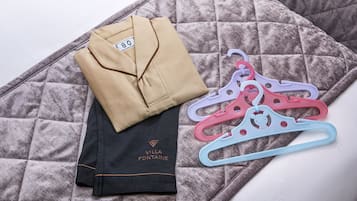 Una camisa beige cuidadosamente doblada con una etiqueta que indica “80” y una camisa negra con el bordado “VILLA FONTAINE”, junto con sujetapapeles de colores.