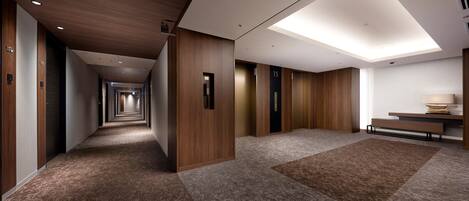 A modern hotel corridor with wooden paneling, carpeted floors, and a skylight.