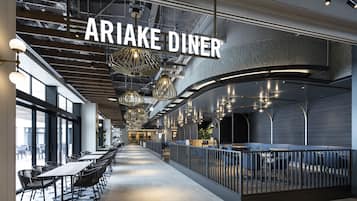 A modern dining area with a long counter, black chairs, and hanging pendant lights.