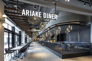 A modern dining area with a long counter, black chairs, and hanging pendant lights.