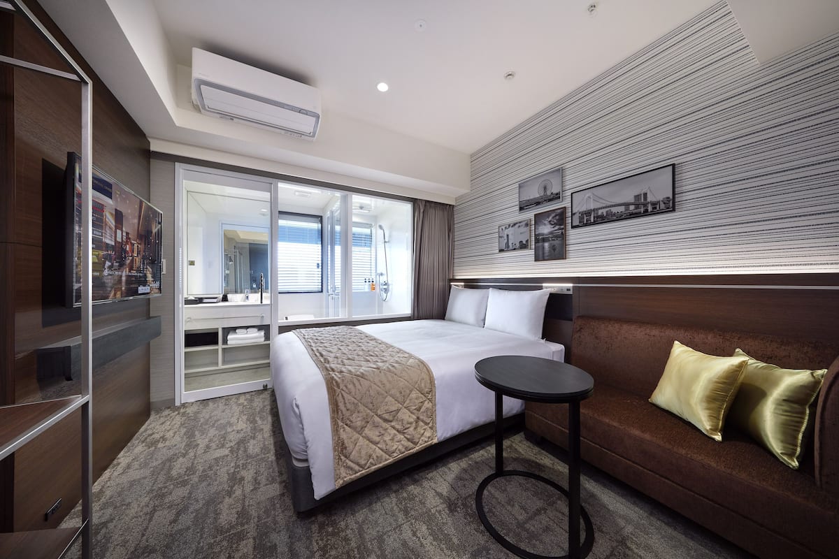 Une chambre d’hôtel avec un lit, un canapé, une petite table ronde et un mur orné de tableaux.