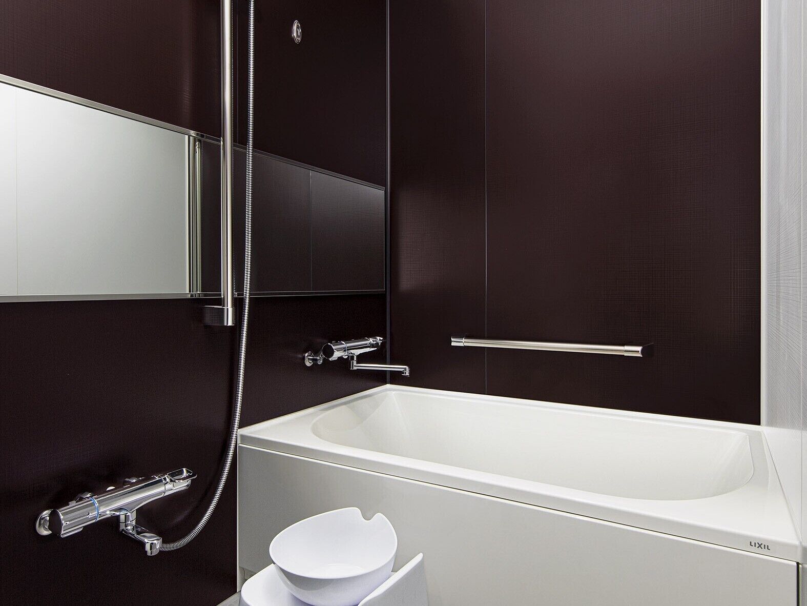 A modern bathroom with a white bathtub, a handheld showerhead, a toilet, and a sink.