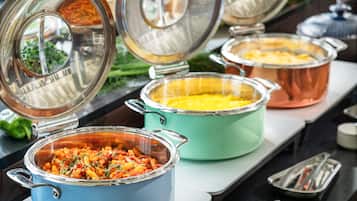 A buffet with various dishes in covered pots, including pasta and a casserole.