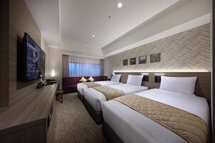 Una habitación de hotel con dos camas, televisión, escritorio y ventana con cortinas.