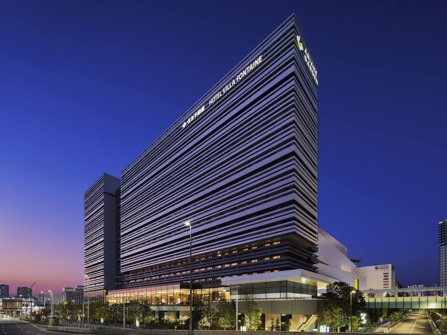A modern hotel with a prominent horizontal facade and a rooftop terrace.