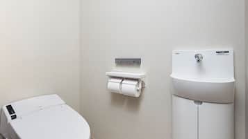 Un baño moderno con inodoro, dispensador de toallas de papel y lavamanos.