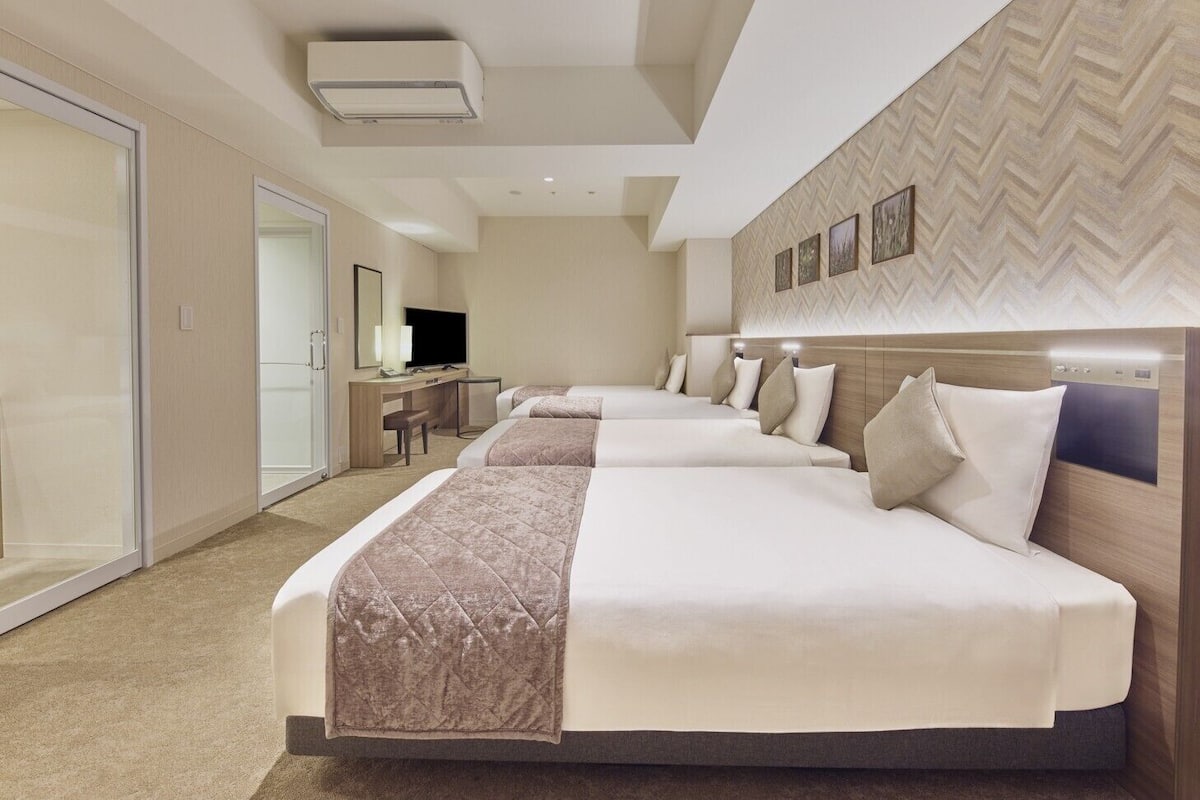 Une chambre d’hôtel avec un grand lit, un bureau, une télévision et un mur orné d’un motif en chevrons.